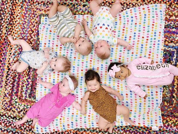 babies lying on a colorful patterned blanket